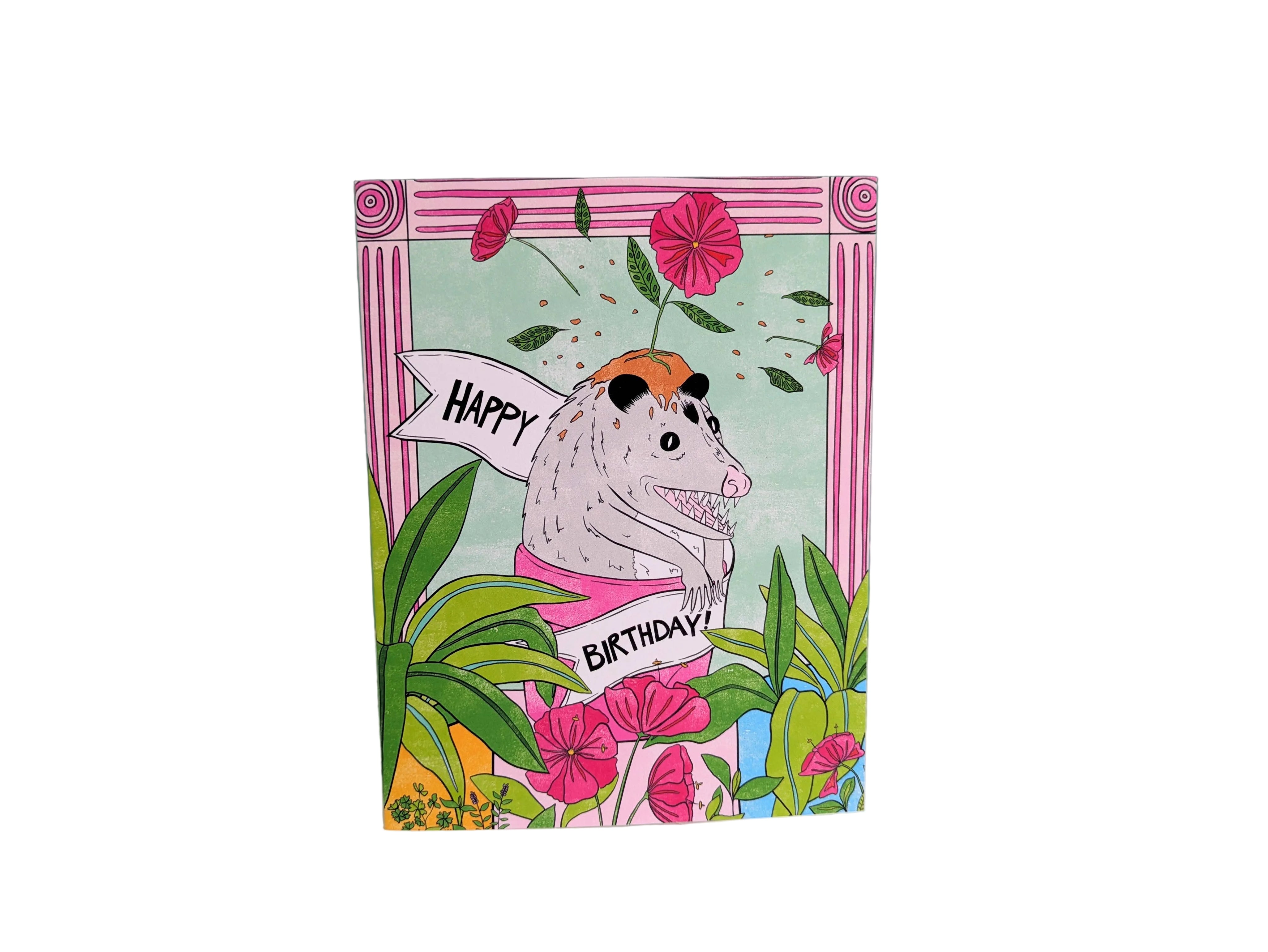Birthday card with a cartoon raccoon holding a banner on a green tiled background